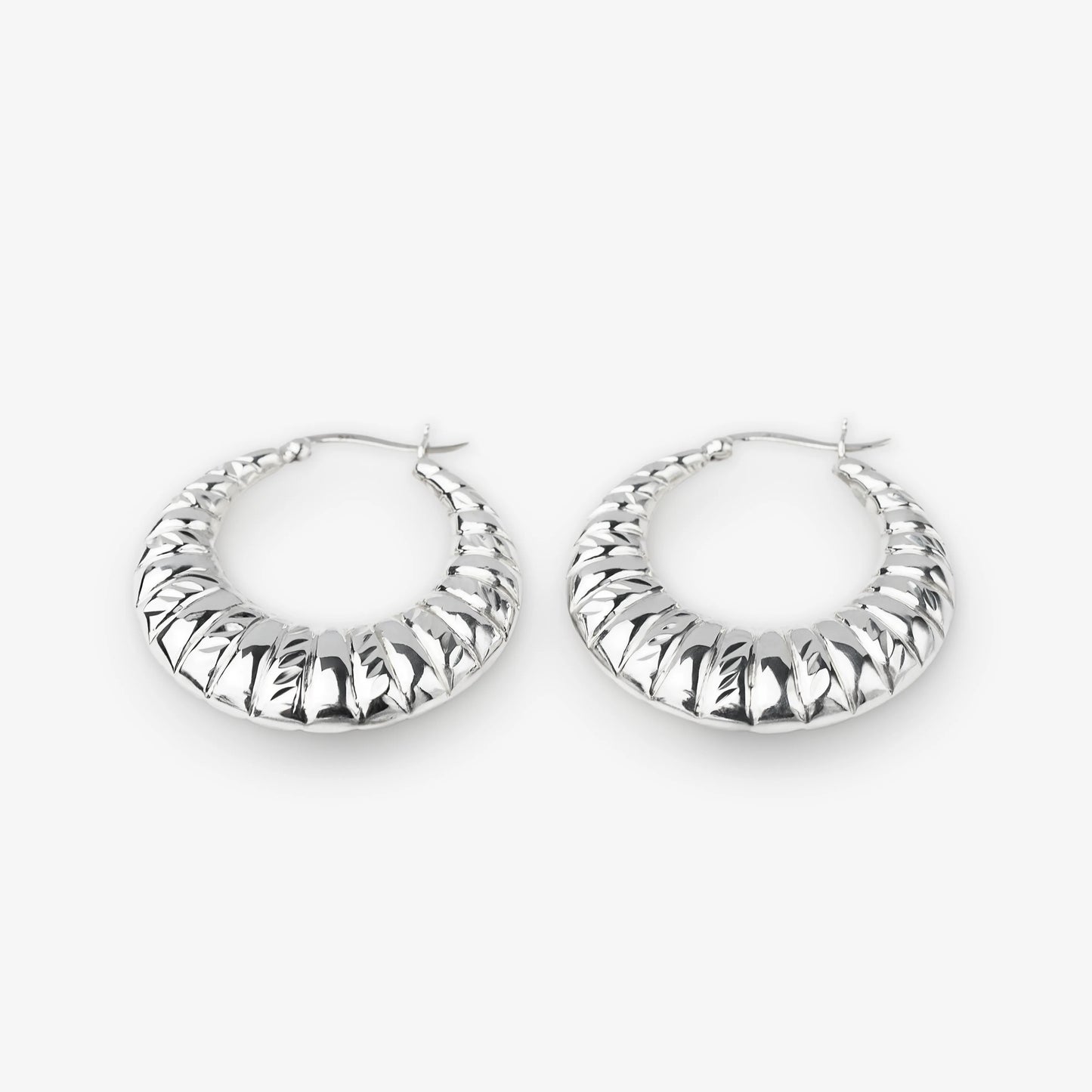 A pair of textured silver hoop earrings with a ribbed, ridged outer surface, displayed on a clean light gray background.