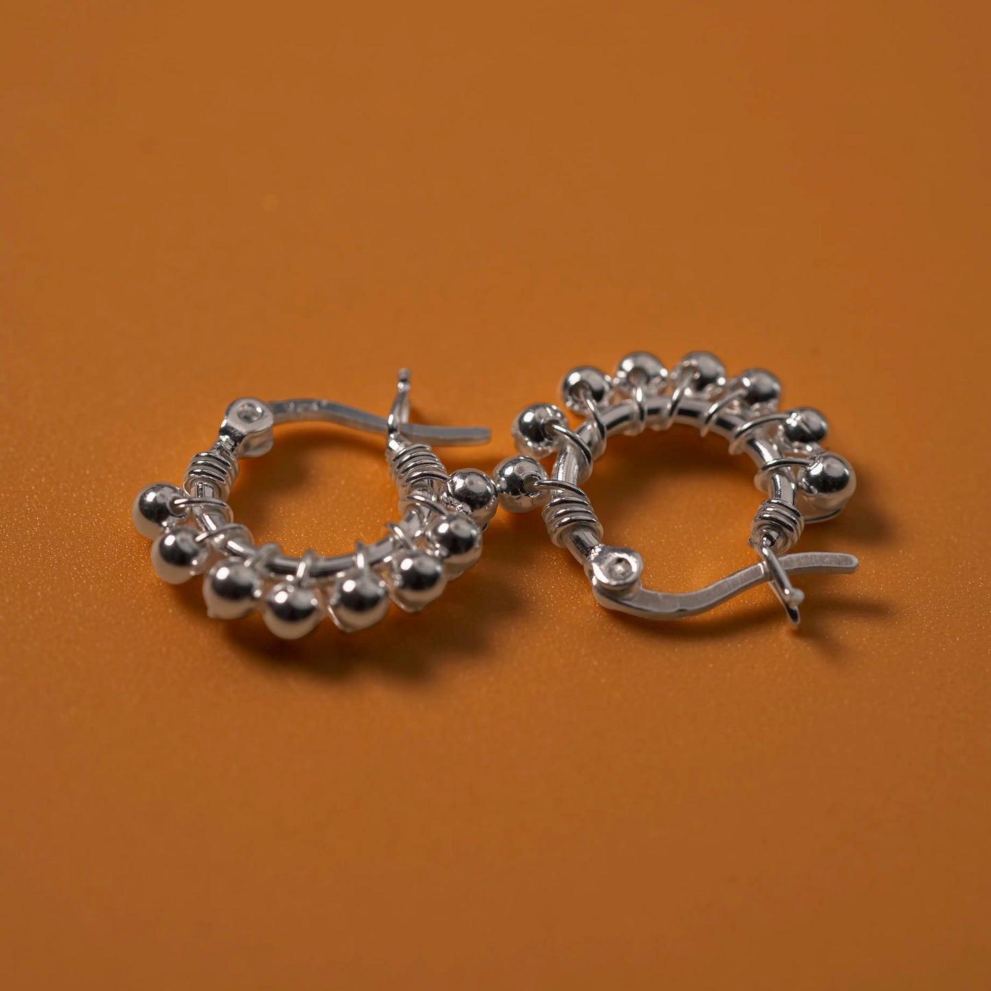 Beautiful Sterling Silver Ball Adorned Earrings on Orange Background.