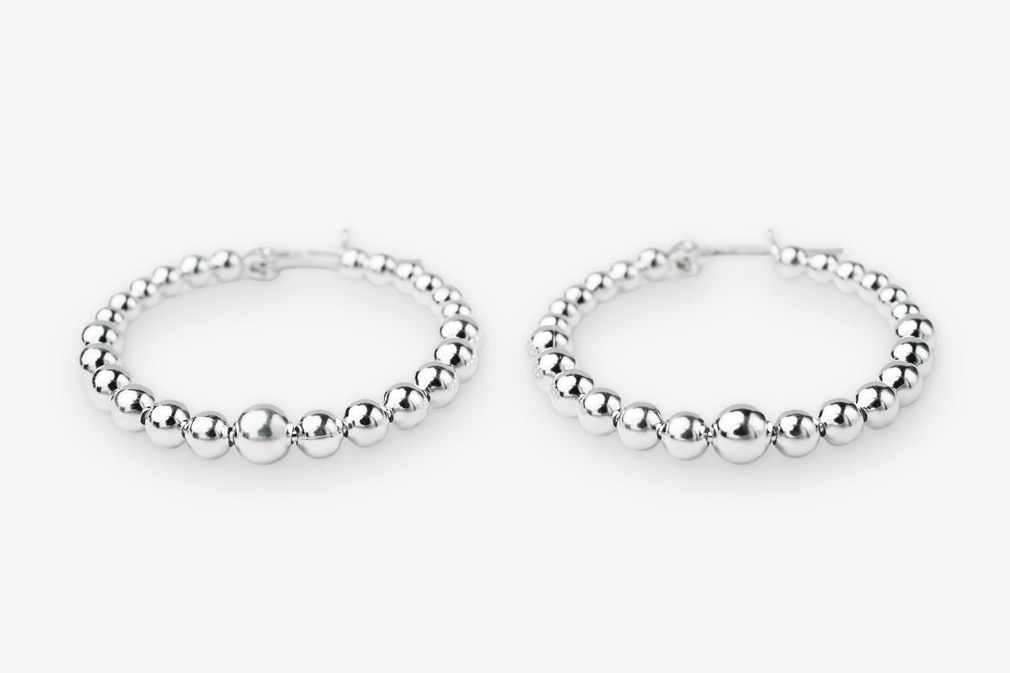 A pair of silver beaded hoop earrings with a polished metallic finish, displayed on a clean white background.