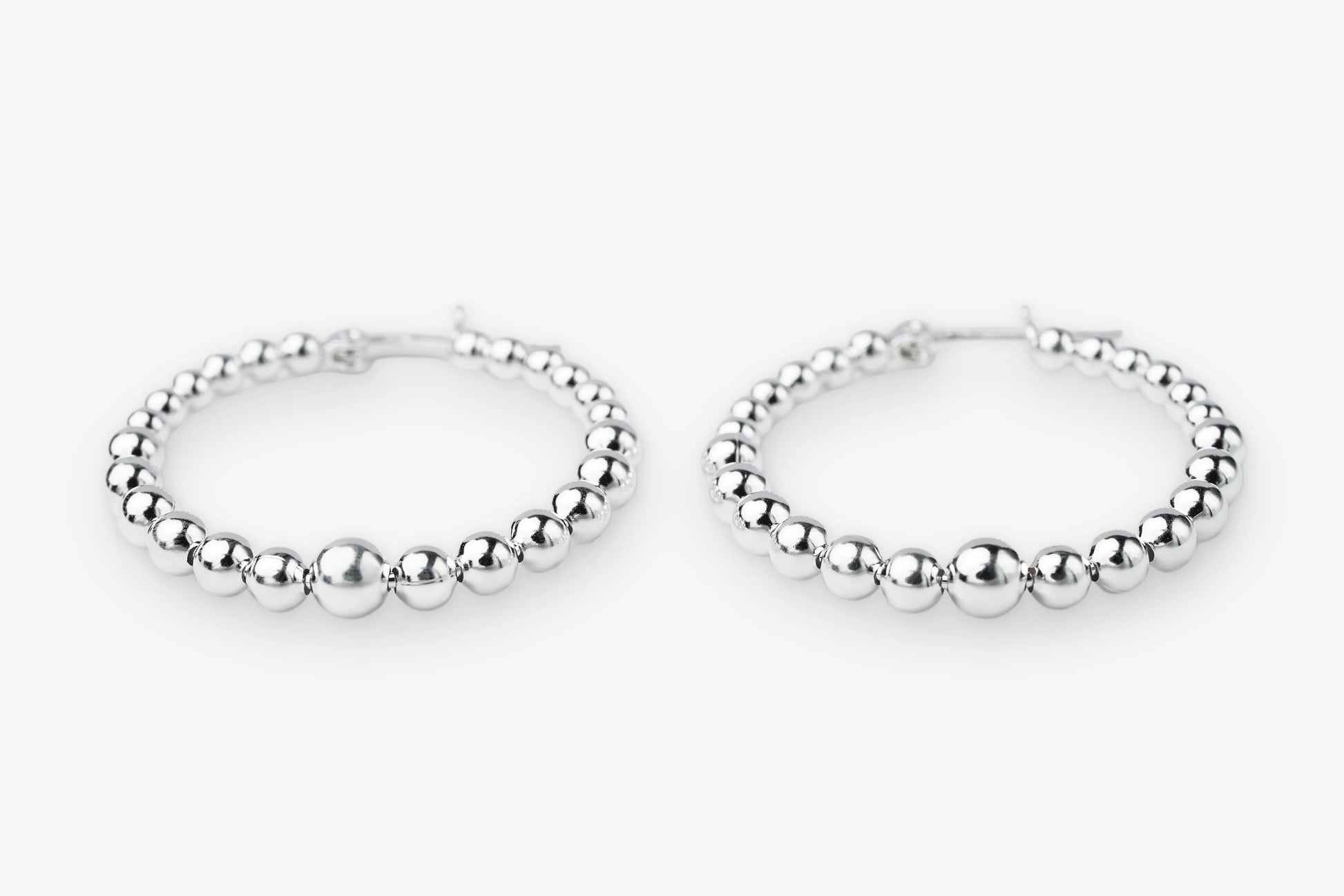 A pair of silver beaded hoop earrings with a polished metallic finish, displayed on a clean white background.