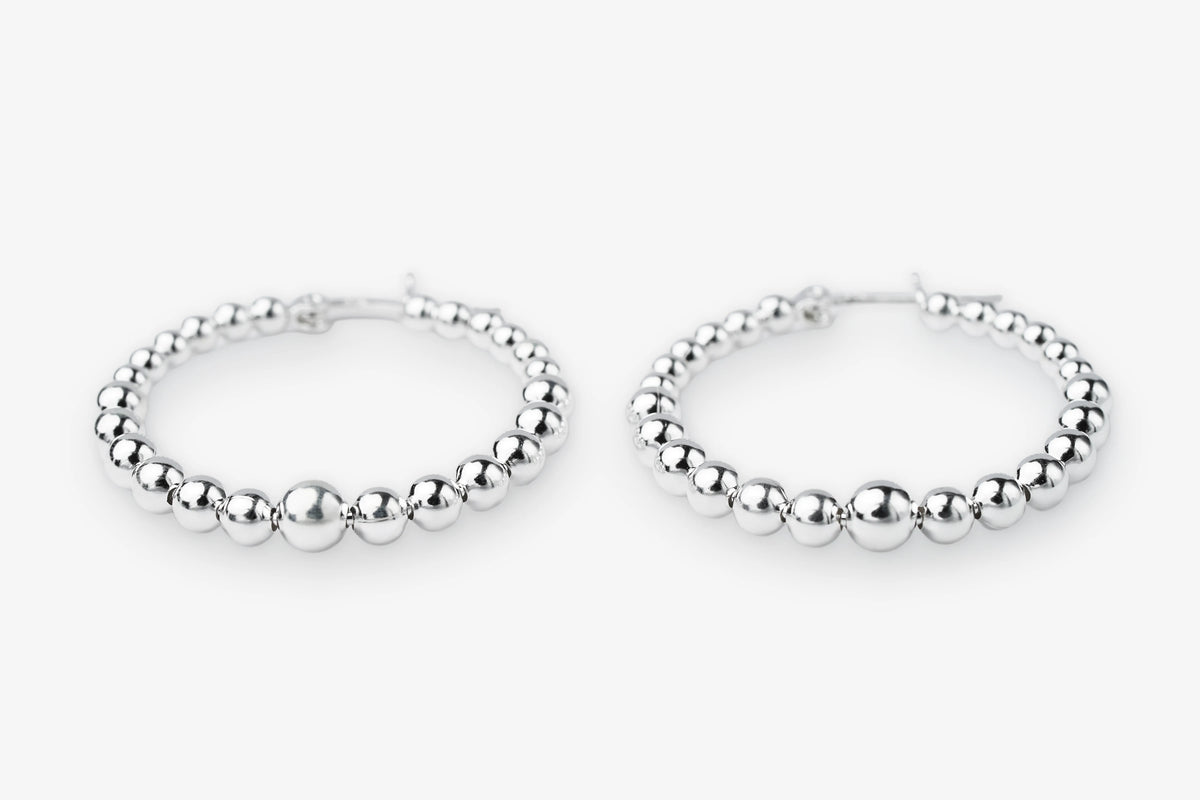 A pair of silver beaded hoop earrings with a polished metallic finish, displayed on a clean white background.