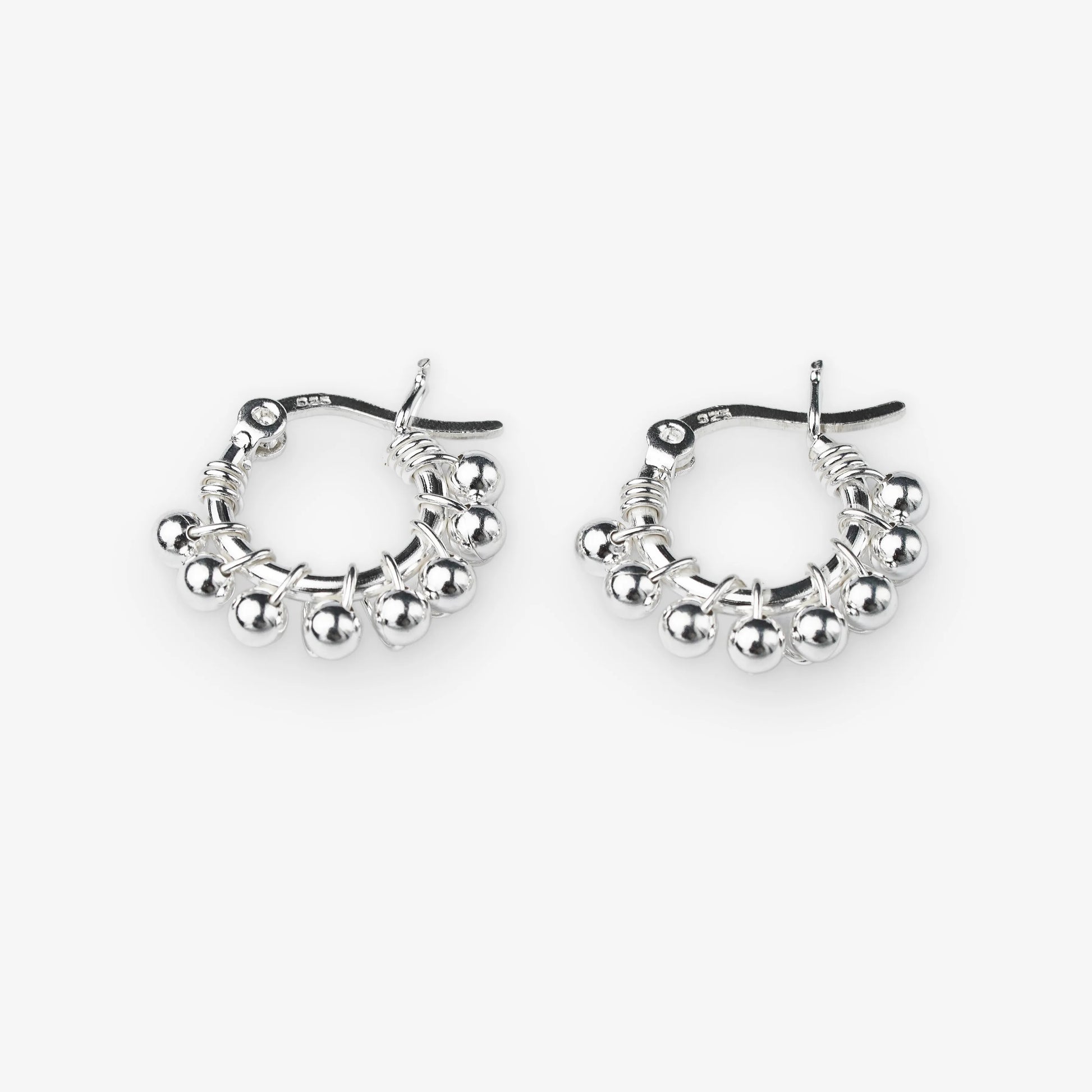 A pair of silver hoop earrings with dangling beaded fringe and a textured wire design, shown on a light gray background.