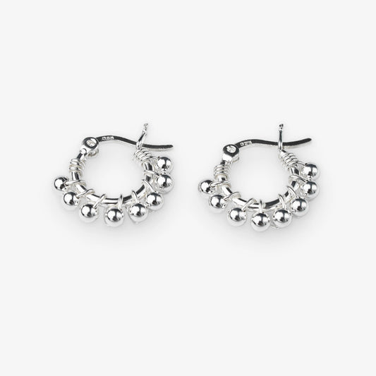 A pair of silver hoop earrings with dangling beaded fringe and a textured wire design, shown on a light gray background.