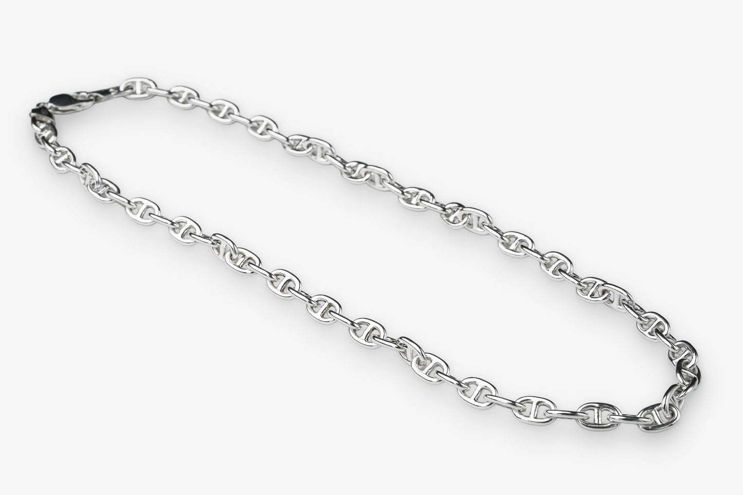 A silver-toned metal chain necklace with repeating interlocking links, arranged in a loose loop on a plain light gray background.