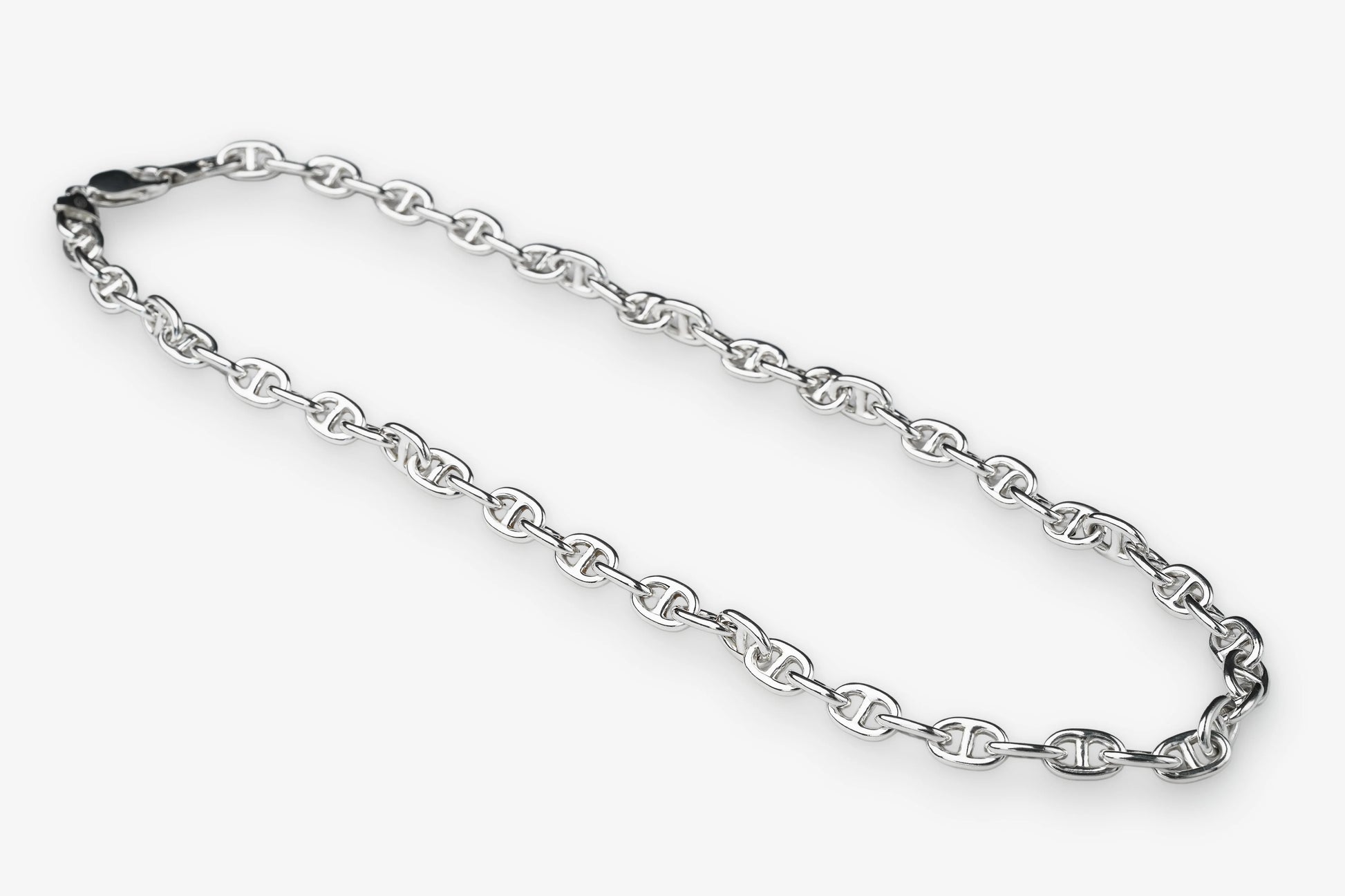 A silver-toned metal chain necklace with repeating interlocking links, arranged in a loose loop on a plain light gray background.