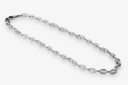 A silver-toned metal chain necklace with repeating interlocking links, arranged in a loose loop on a plain light gray background.