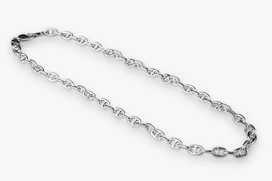 A silver-toned metal chain necklace with repeating interlocking links, arranged in a loose loop on a plain light gray background.