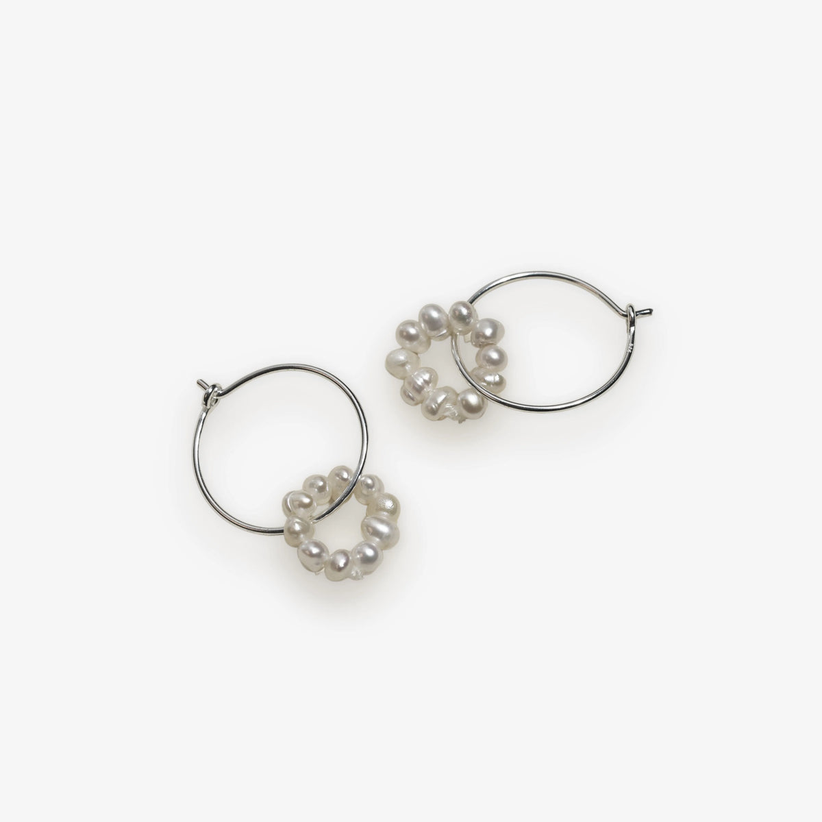 silver wire hoop dangled with pearl on a off white background.